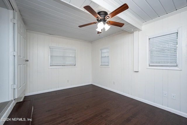 empty room featuring ceiling fan, dark wood-type flooring, wood walls, and ornamental molding