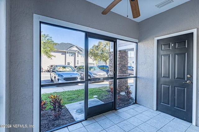 doorway to outside with ceiling fan and light tile patterned flooring