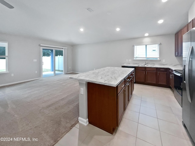 kitchen with sink, ceiling fan, a kitchen island, light colored carpet, and stainless steel appliances