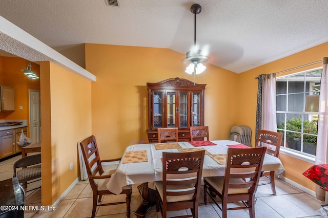 dining area featuring light tile patterned floors, a textured ceiling, ceiling fan, and lofted ceiling