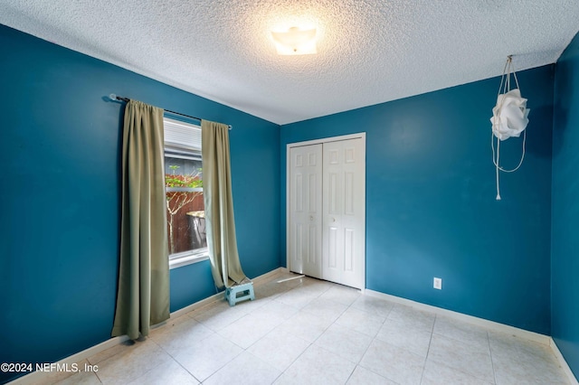 unfurnished bedroom featuring a textured ceiling and a closet