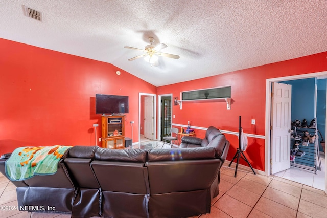 living room featuring ceiling fan, lofted ceiling, a textured ceiling, and light tile patterned floors