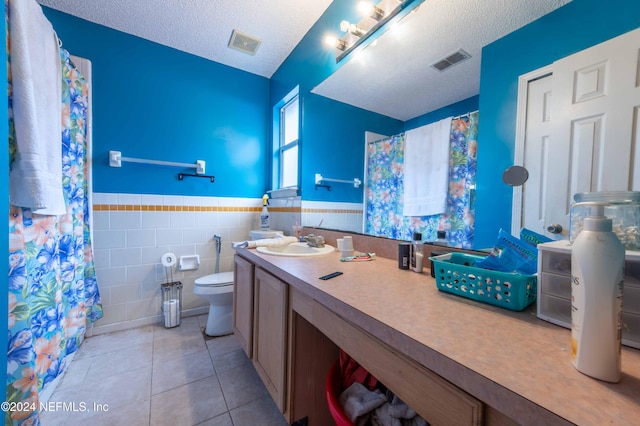 bathroom featuring toilet, a textured ceiling, tile patterned floors, and tile walls