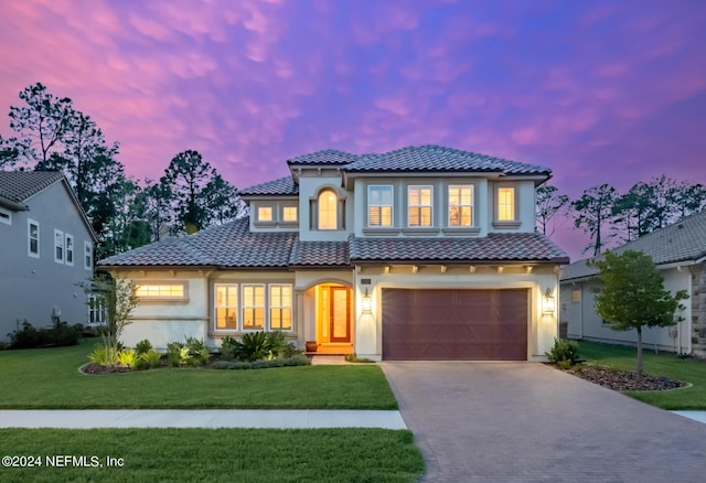 mediterranean / spanish-style home featuring a garage and a lawn