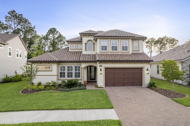 mediterranean / spanish home featuring a garage and a front lawn