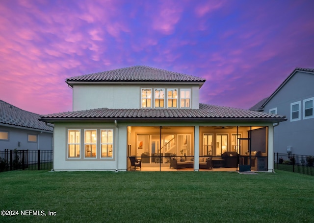 back house at dusk with a sunroom and a yard