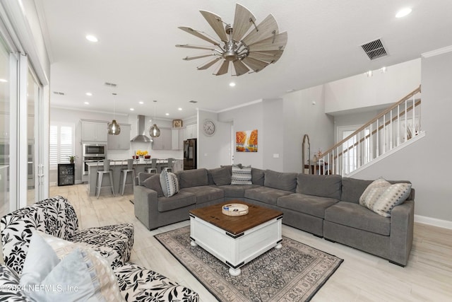 living room with ceiling fan and ornamental molding