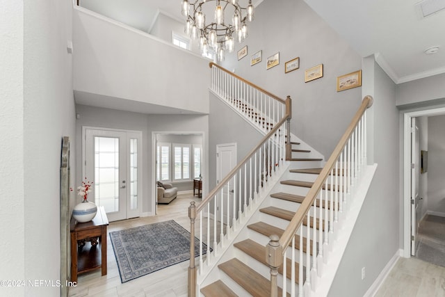 foyer with a chandelier, a towering ceiling, and ornamental molding