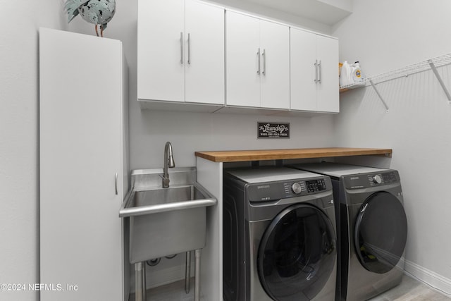 laundry room featuring cabinets, separate washer and dryer, sink, and light wood-type flooring