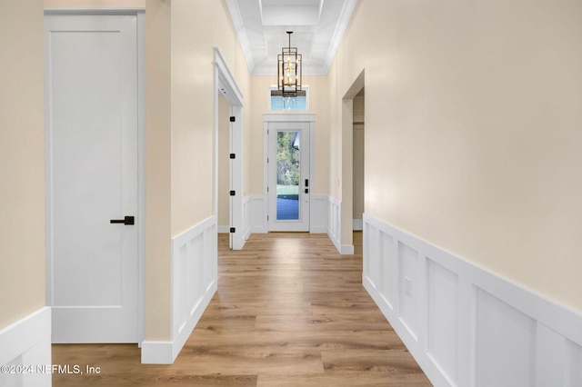 corridor with crown molding, light hardwood / wood-style flooring, and a chandelier