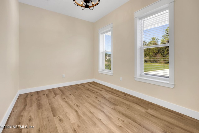 spare room featuring a wealth of natural light, light hardwood / wood-style flooring, and a notable chandelier