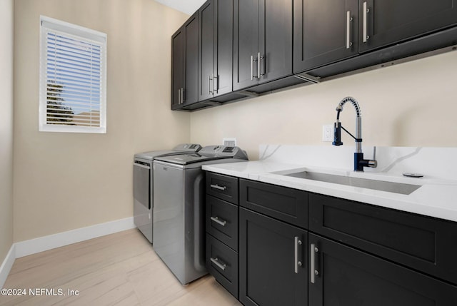 washroom featuring washing machine and clothes dryer, sink, and cabinets