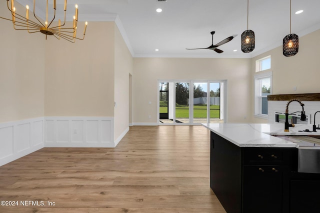 kitchen featuring ceiling fan with notable chandelier, sink, hanging light fixtures, ornamental molding, and light hardwood / wood-style floors