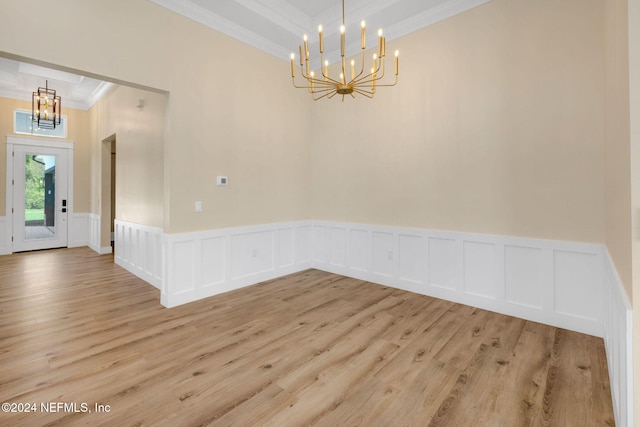 empty room with a chandelier, light hardwood / wood-style floors, and ornamental molding