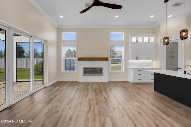 unfurnished living room with heating unit, ceiling fan, light hardwood / wood-style flooring, and ornamental molding