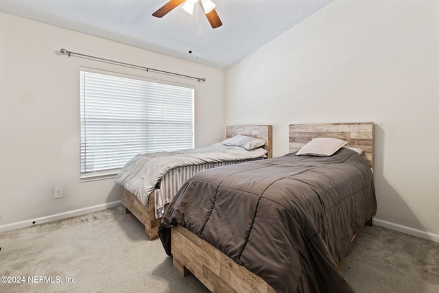 bedroom featuring multiple windows, ceiling fan, light carpet, and a textured ceiling