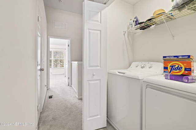 clothes washing area with washer and dryer and light colored carpet