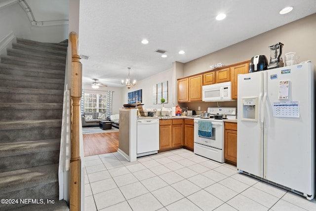 kitchen with pendant lighting, white appliances, ceiling fan with notable chandelier, light wood-type flooring, and a textured ceiling