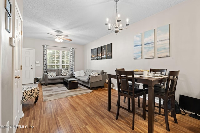 dining space featuring hardwood / wood-style floors, ceiling fan with notable chandelier, and a textured ceiling