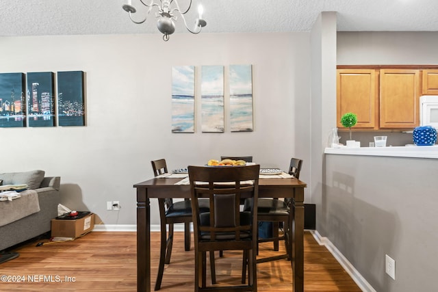 dining area with an inviting chandelier, a textured ceiling, and light wood-type flooring