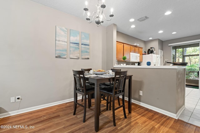 dining area featuring a chandelier, a textured ceiling, and hardwood / wood-style flooring