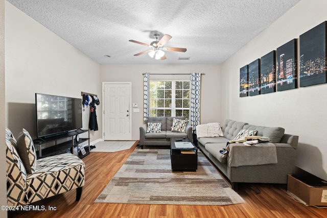 living room with a textured ceiling, hardwood / wood-style flooring, and ceiling fan