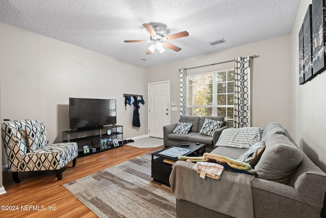 living room with hardwood / wood-style flooring, ceiling fan, and a textured ceiling