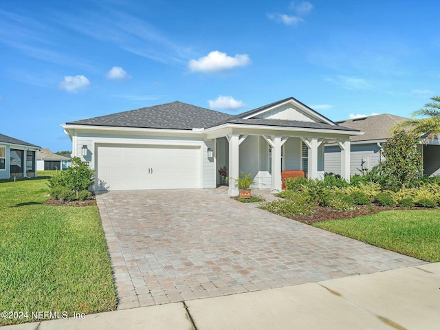 view of front of home featuring covered porch, a front yard, and a garage