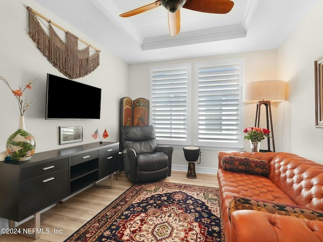 living room featuring hardwood / wood-style flooring, a raised ceiling, and crown molding