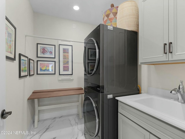 washroom with stacked washer / dryer, sink, and cabinets