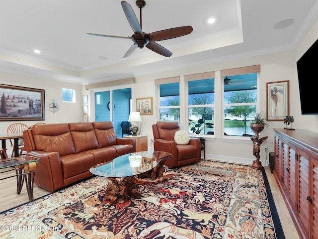 living room with a tray ceiling, light hardwood / wood-style flooring, ceiling fan, and ornamental molding