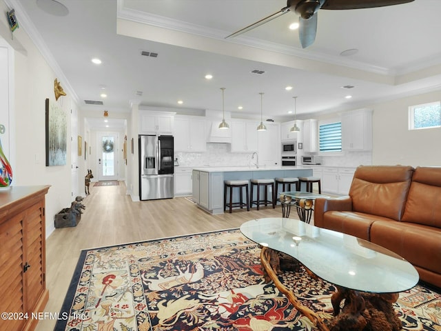 living room featuring a healthy amount of sunlight, light hardwood / wood-style flooring, ceiling fan, and ornamental molding