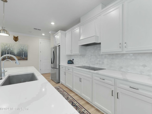 kitchen featuring sink, stainless steel fridge with ice dispenser, premium range hood, black electric stovetop, and white cabinets