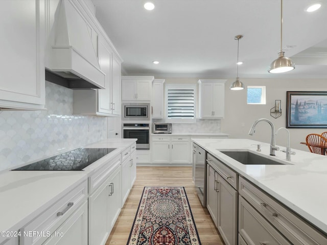 kitchen featuring sink, white cabinets, custom range hood, and appliances with stainless steel finishes