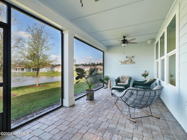 sunroom / solarium with ceiling fan and a water view