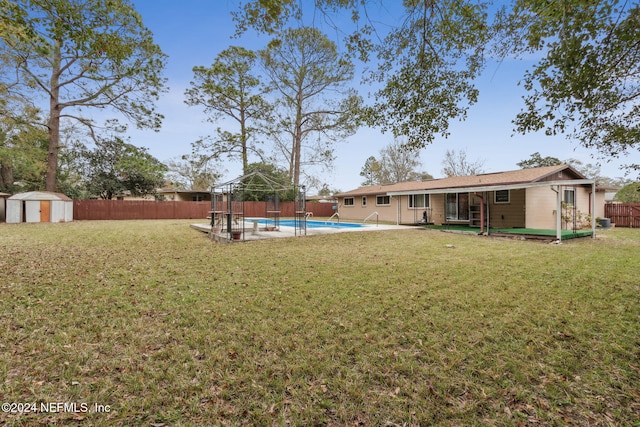 view of yard with a patio, a fenced in pool, and a shed