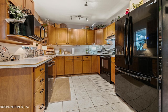 kitchen featuring black appliances, light tile patterned floors, and sink