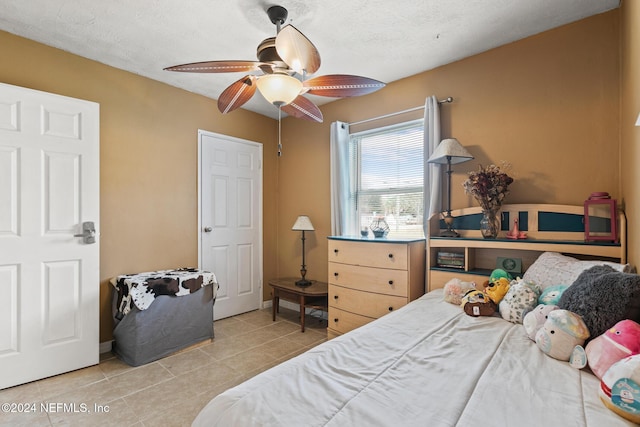 tiled bedroom featuring ceiling fan and a textured ceiling