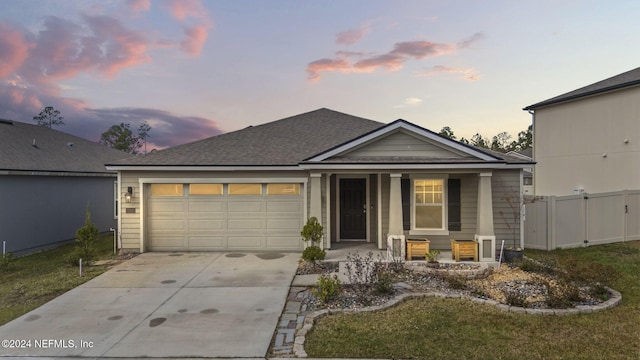 view of front of home featuring covered porch, a garage, and a lawn