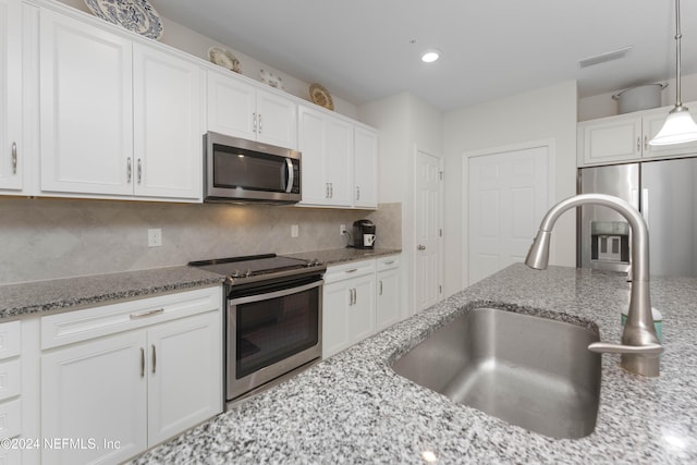 kitchen with pendant lighting, white cabinets, stainless steel appliances, and sink