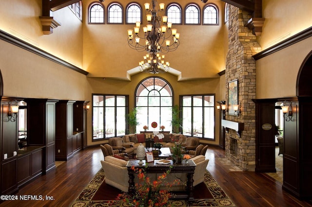 living room with a towering ceiling, dark wood-type flooring, a healthy amount of sunlight, and a notable chandelier