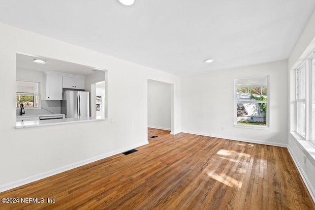 unfurnished living room with hardwood / wood-style floors and sink