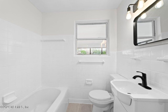 bathroom with tile patterned floors, a washtub, tile walls, and toilet