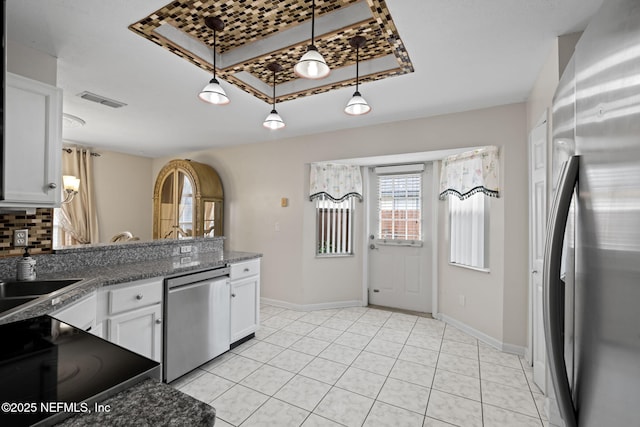 kitchen with stainless steel appliances, dark stone counters, white cabinets, decorative light fixtures, and sink