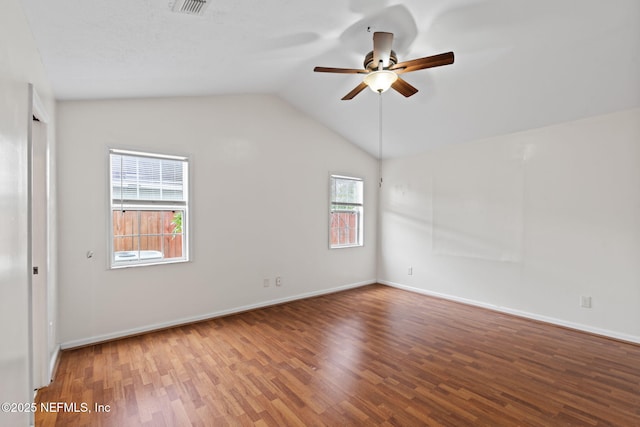 empty room with lofted ceiling, hardwood / wood-style floors, and ceiling fan