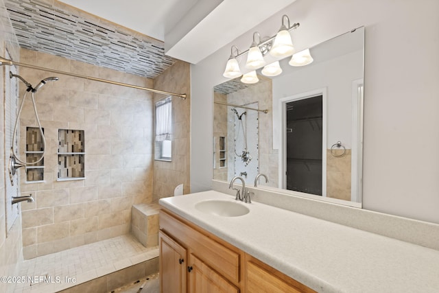 bathroom with a tile shower and vanity