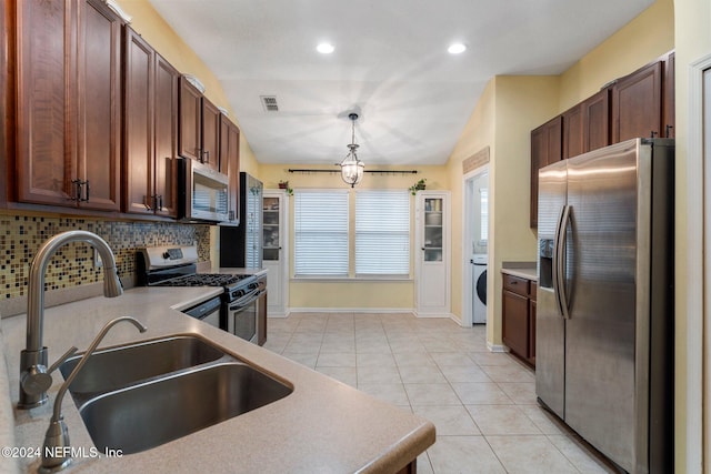 kitchen featuring tasteful backsplash, stainless steel appliances, vaulted ceiling, sink, and washer / clothes dryer