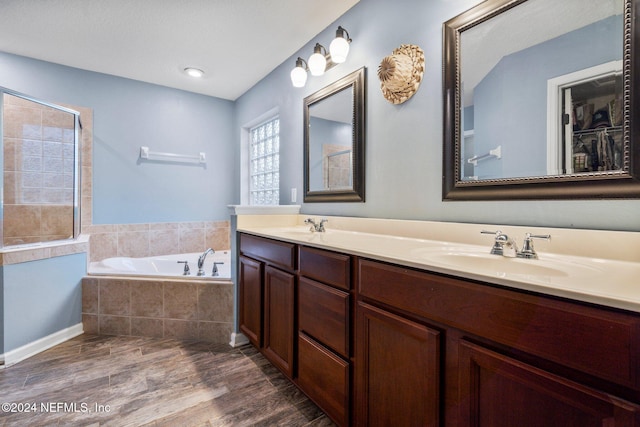 bathroom featuring tiled bath, hardwood / wood-style floors, and vanity