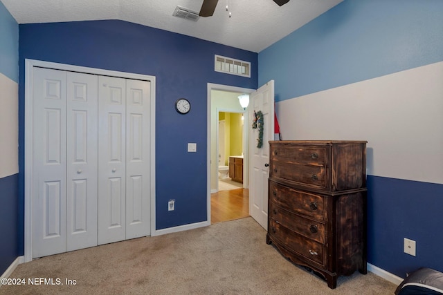 carpeted bedroom with a textured ceiling, a closet, vaulted ceiling, and ceiling fan