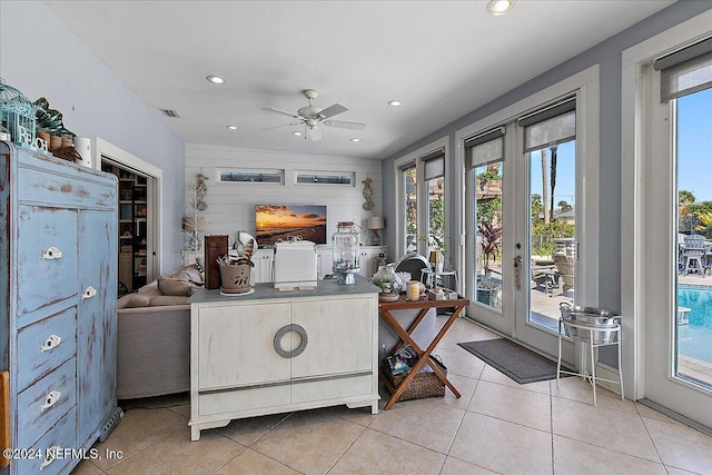 interior space featuring plenty of natural light, wood walls, ceiling fan, and french doors